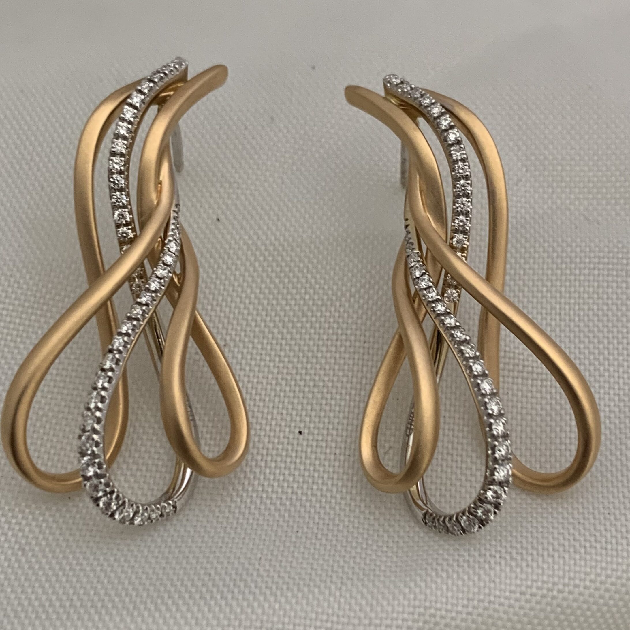 Elegant gold and silver twisted loop earrings with embedded stones.