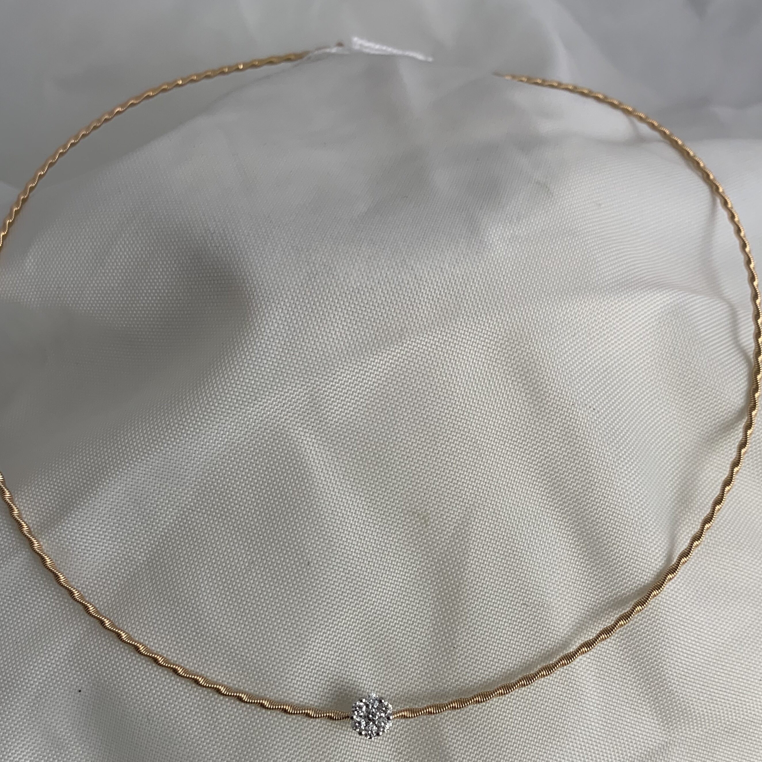 Delicate gold chain necklace with a small central diamond pendant.