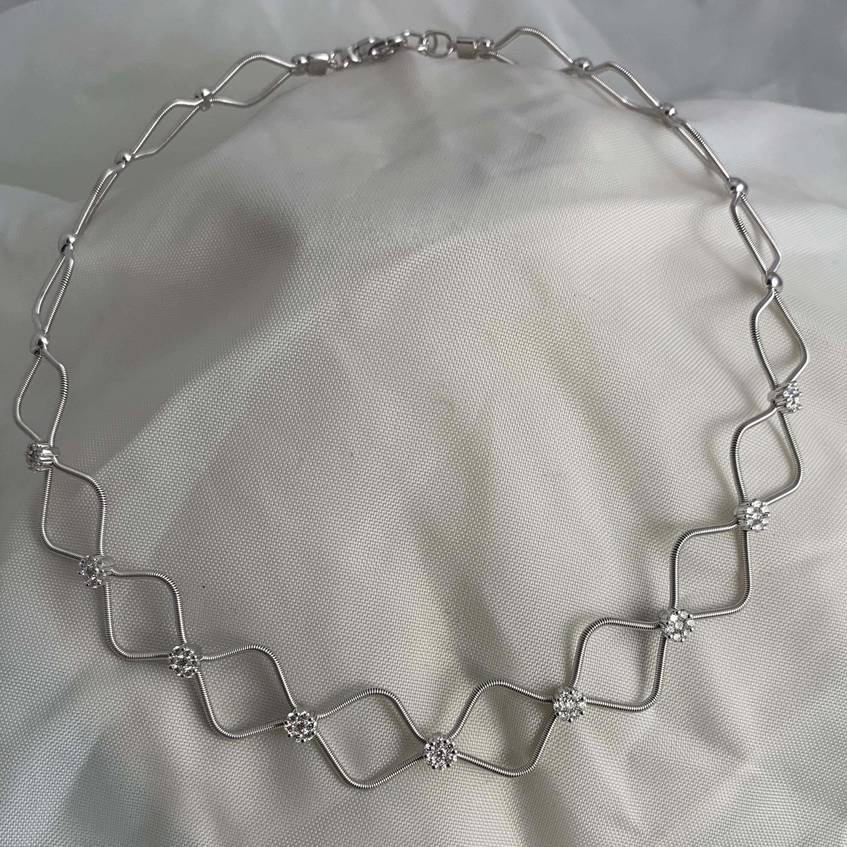 Delicate silver chain necklace with linked geometric diamond shapes.