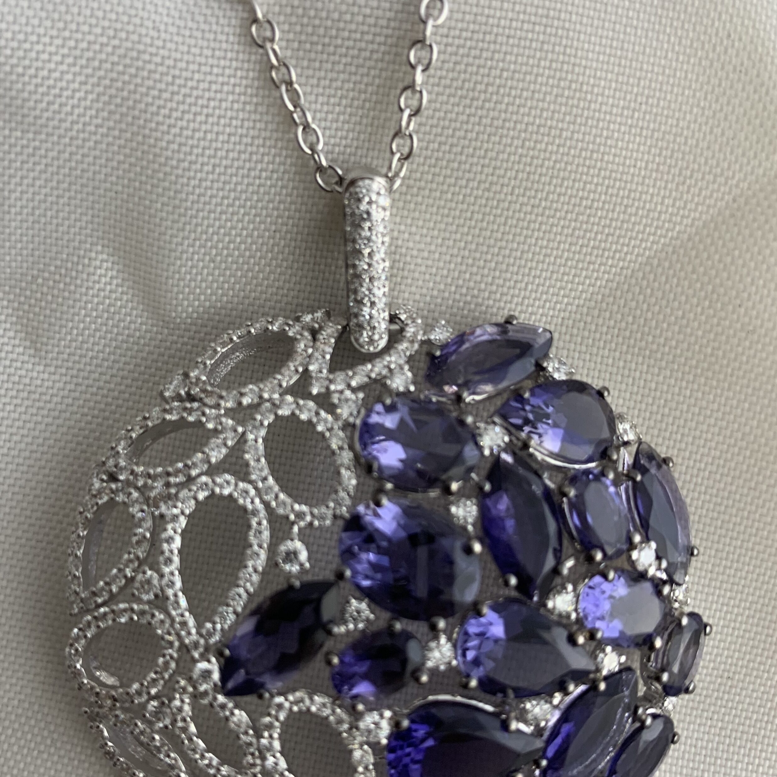Elegant silver pendant with purple gemstones on a chain.