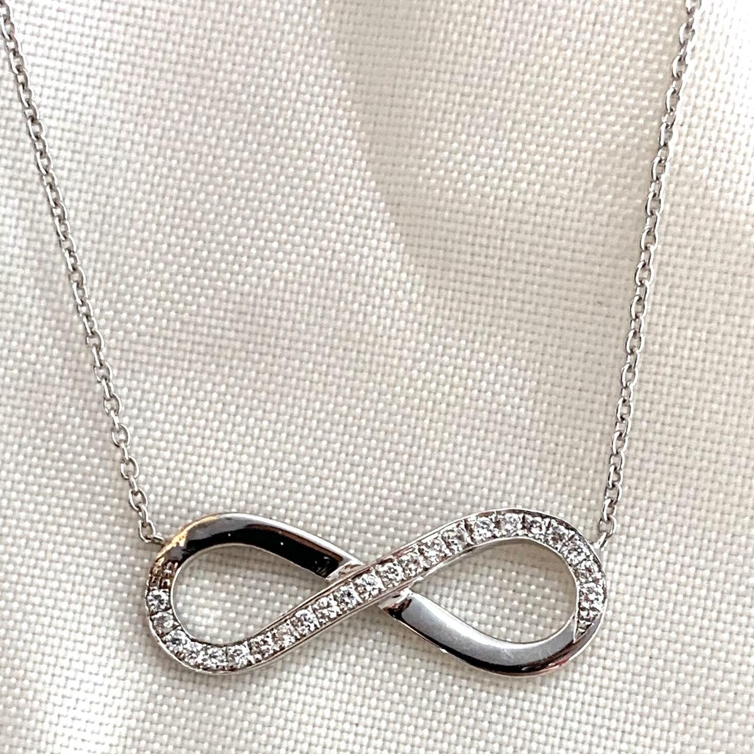 Silver infinity symbol pendant necklace with embedded stones.
