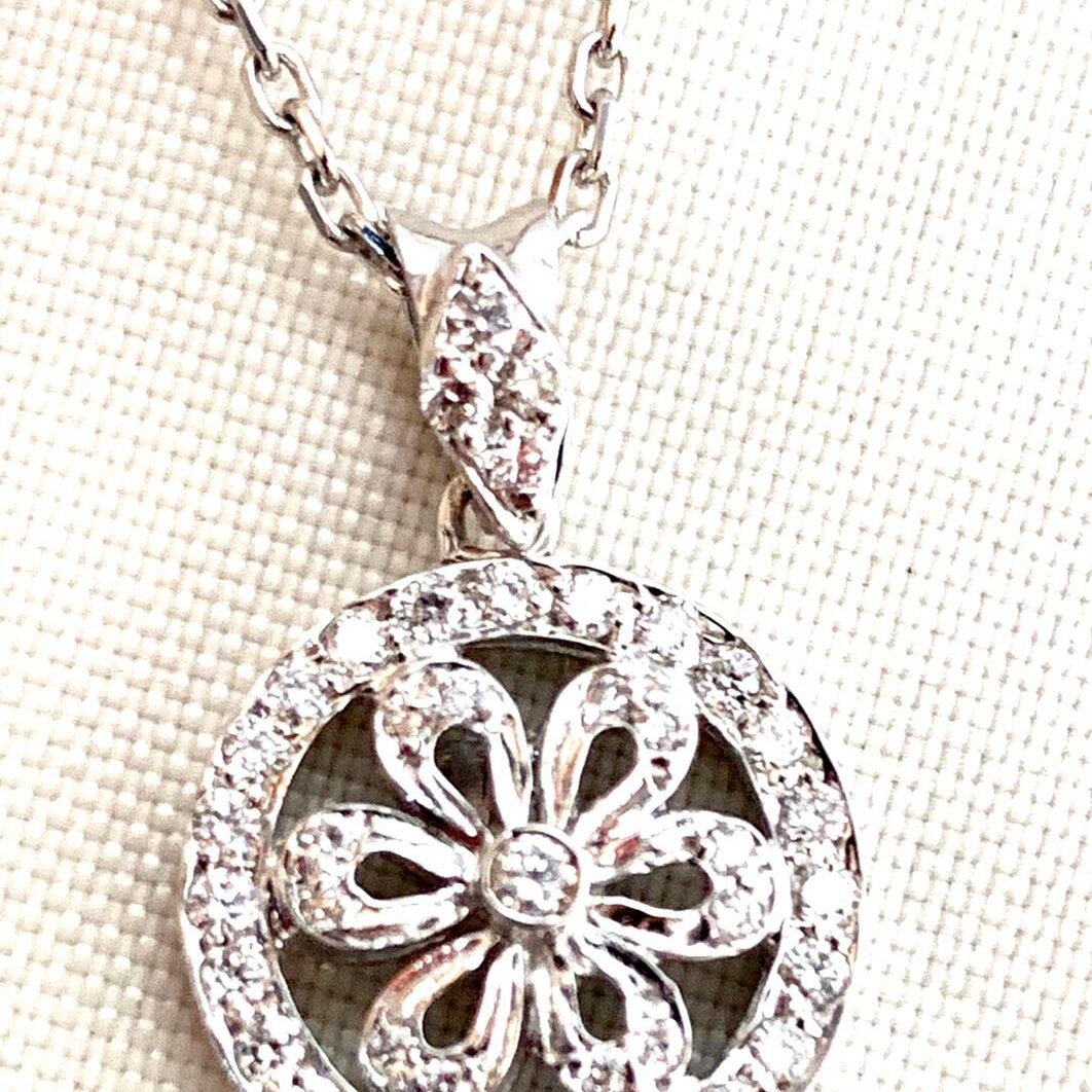 Elegant silver pendant with intricate floral design and sparkling stones.