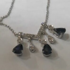 Elegant silver necklace with dark teardrop and clear round stones.