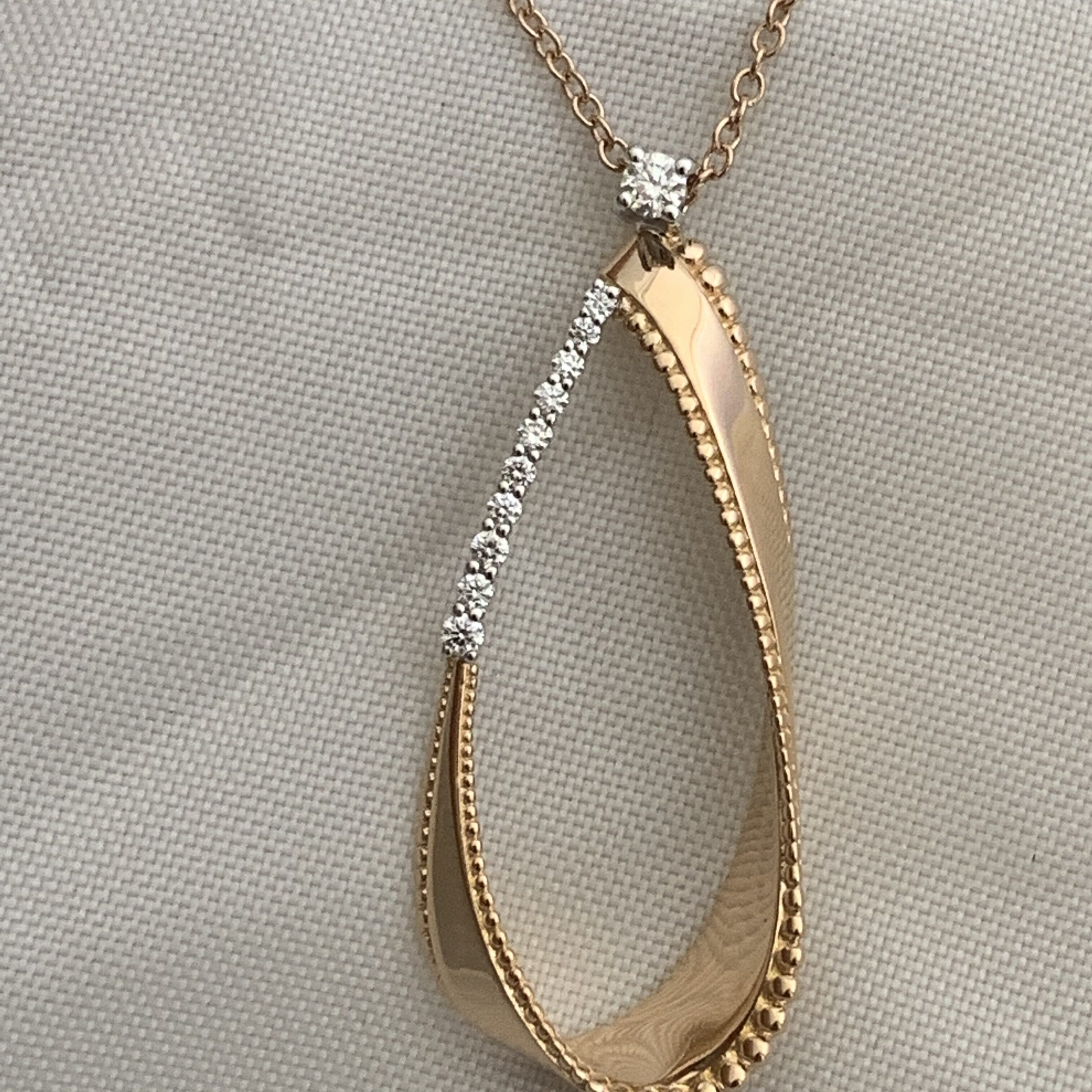 Elegant gold and diamond twisted teardrop pendant on a delicate chain.