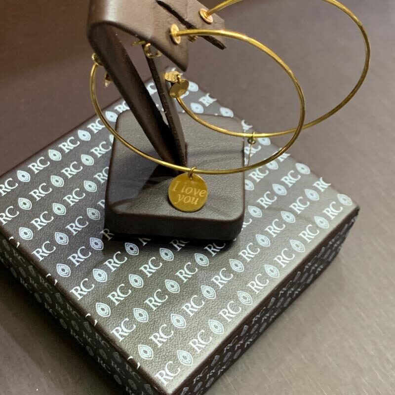 Elegant gold and black bracelet displayed on a stand over a patterned box.