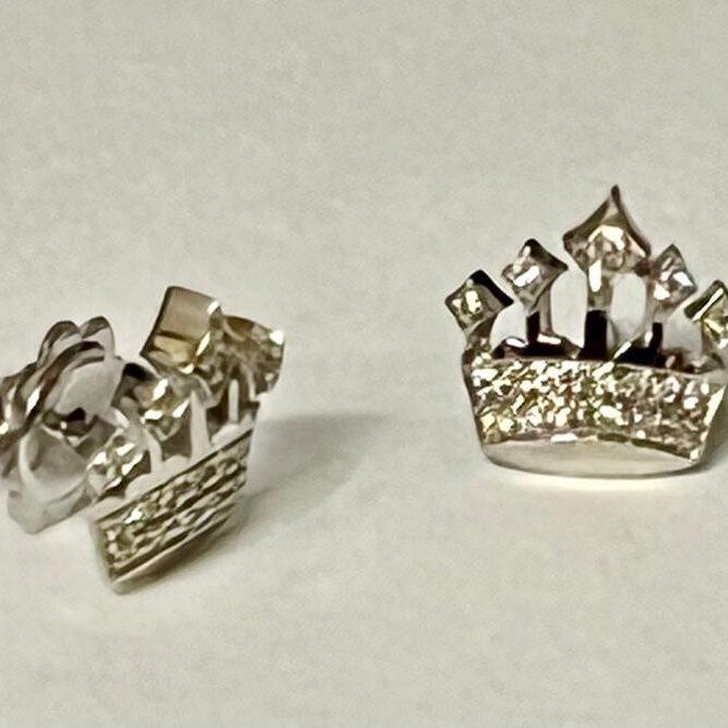 A pair of silver crown-shaped earrings with embedded stones.