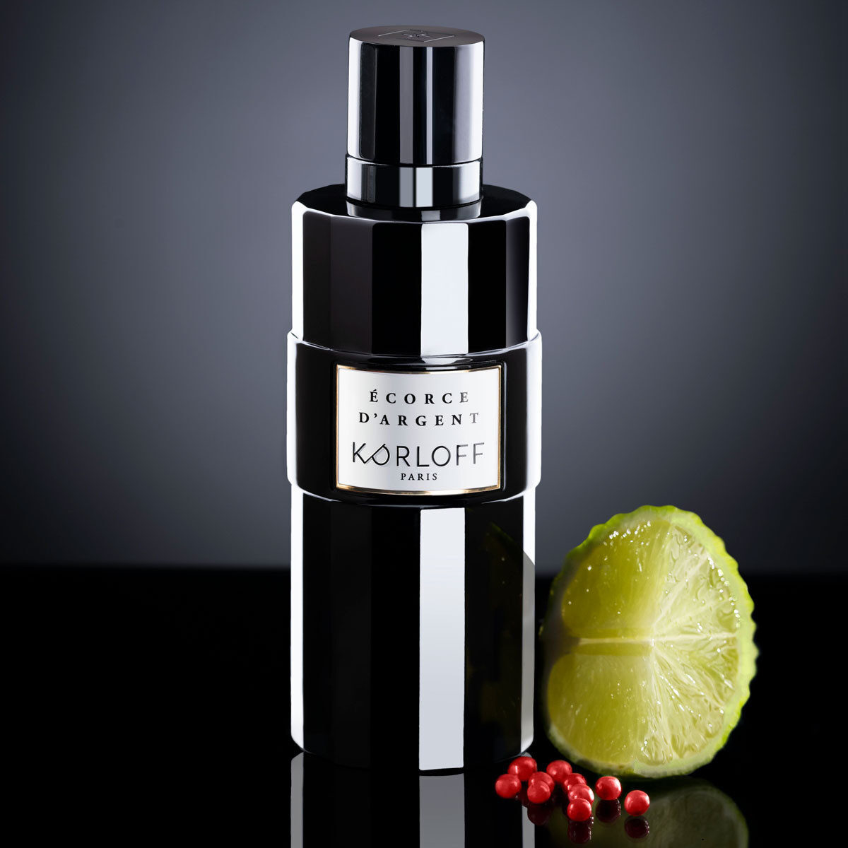 Elegant black bottle of Jean Paul Gaultier perfume with lime and red berries.