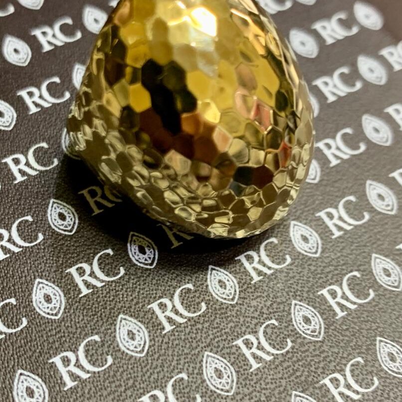 A shiny golden honeycomb-patterned egg on a branded surface.