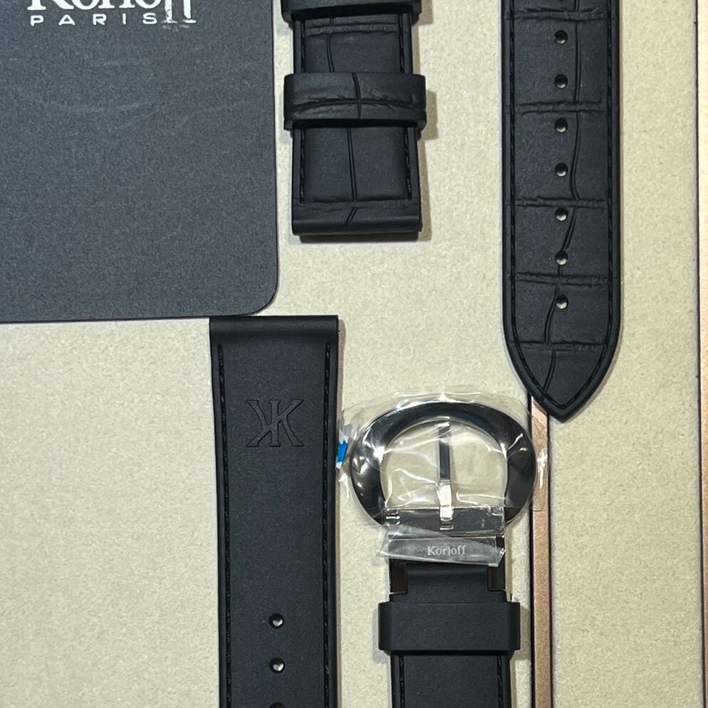 A watch with multiple black straps and a gray box.